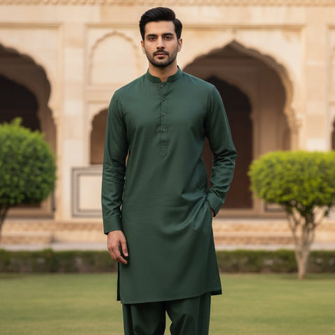 Man wearing a green traditional outfit standing in front of an architectural background