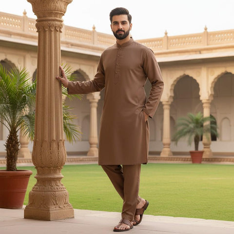 Man in a brown traditional outfit standing in a courtyard with architectural columns and plants.
