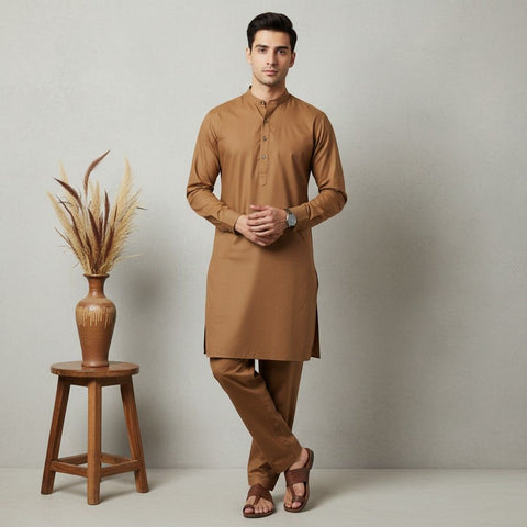 Man wearing a brown kurta with wooden stool and decorative plant on a plain background